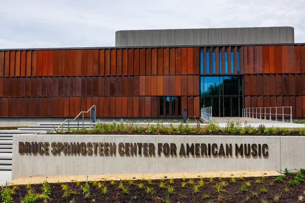 A modernist building with a sign out front reading “Bruce Springsteen Center for American Music.” A modernist building with a sign out front reading “Bruce Springsteen Center for American Music.”