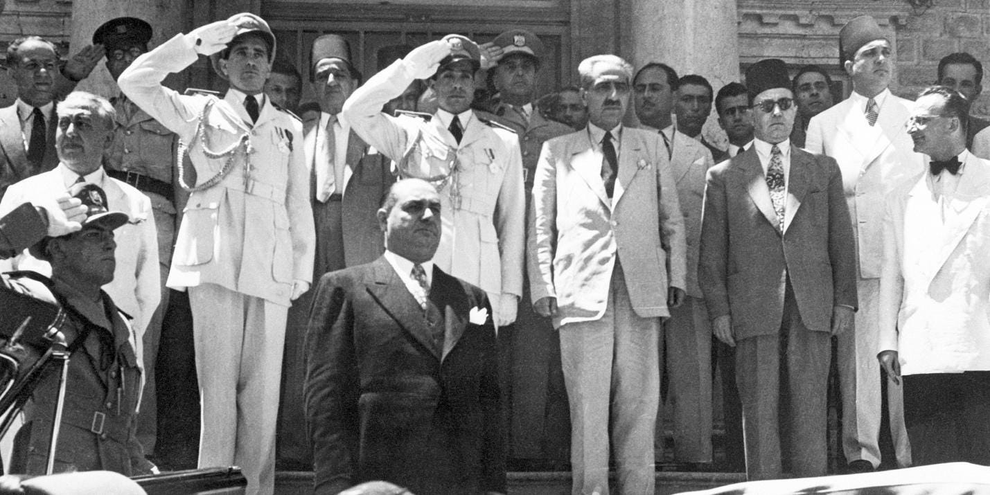 (Original Caption) 7/11/1949-Damascus, Syria- Col. Husni Zaim (center, foreground) stands at attention while the national anthem is played during his recent inauguration in Damascus as President of Syrian republic. Behind him are officers and officials who supported him when he took control of the government in a coup d'etat.