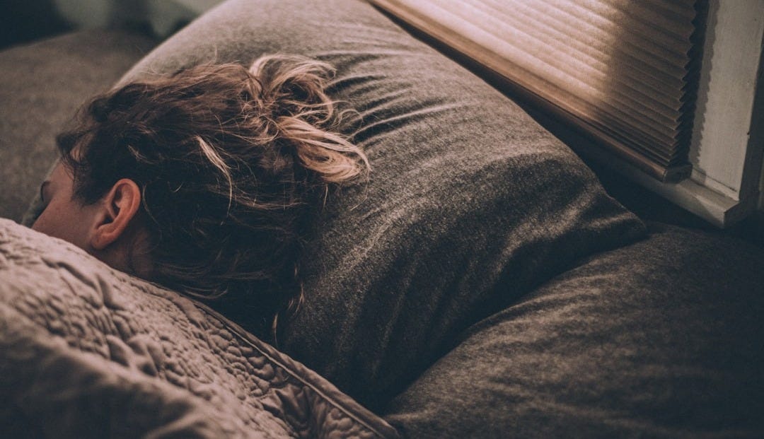woman sleeping on bed under blankets