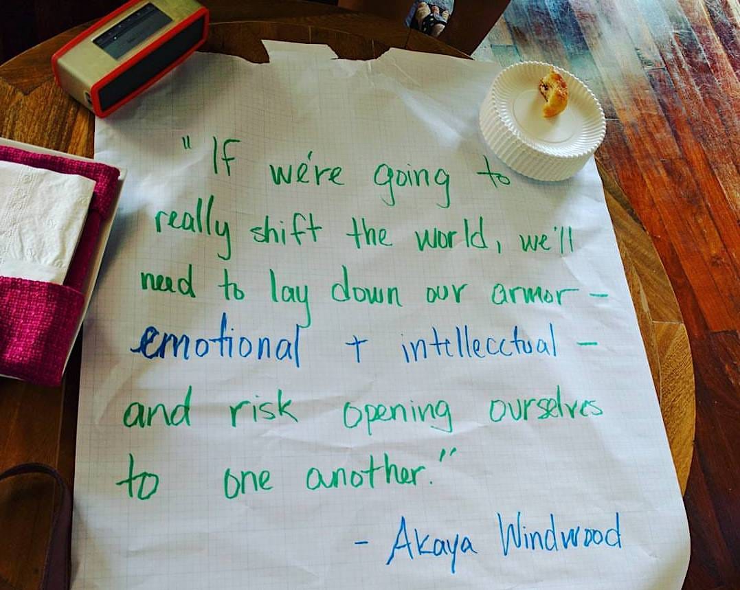 A large piece of chart paper from a workshop has this quote from Akaya written in green and blue marker: "If we're going to really shift the world, we'll need to lay down our armor - emotional and intellectual - and risk opening ourselves to one another."