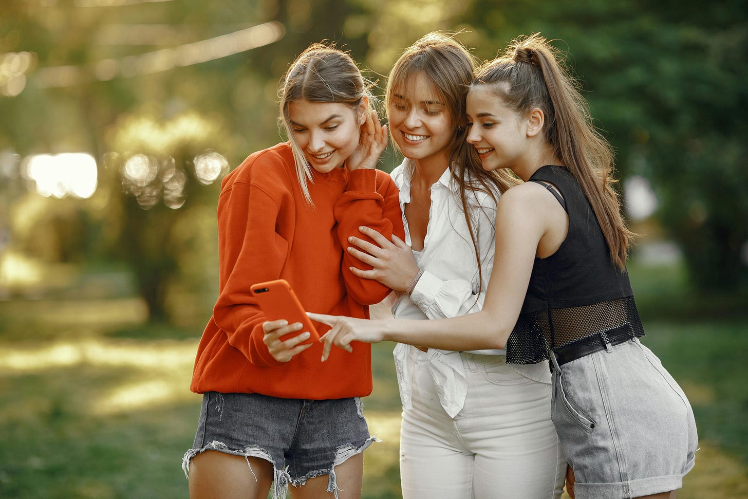 Three women huddled together looking at a cell phone