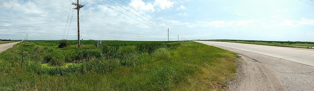 Two roads heading northeast and southeast across wide empty valley with powerlines marching into distance