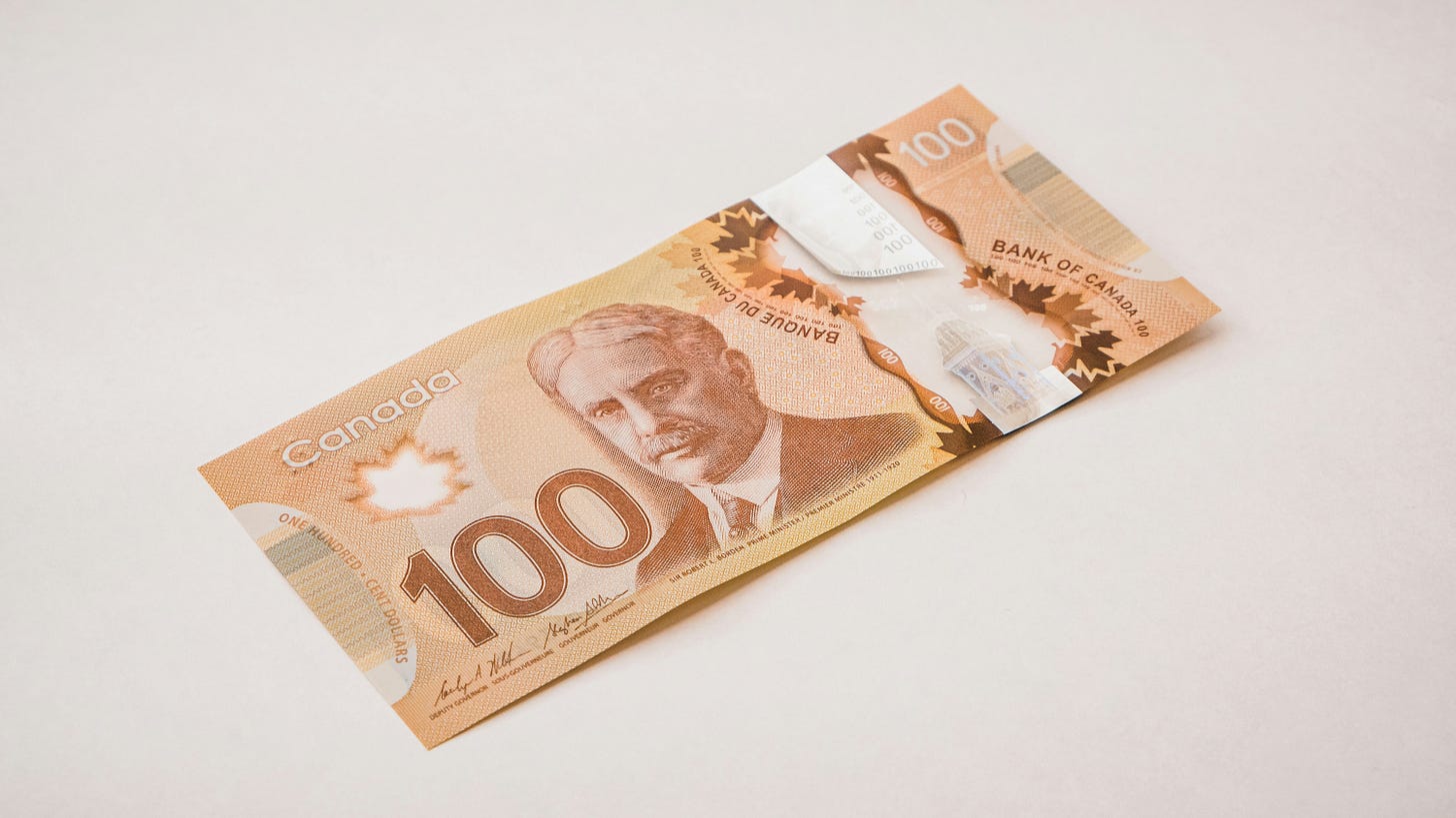 A Canadian 100 dollar bill sits on a white background