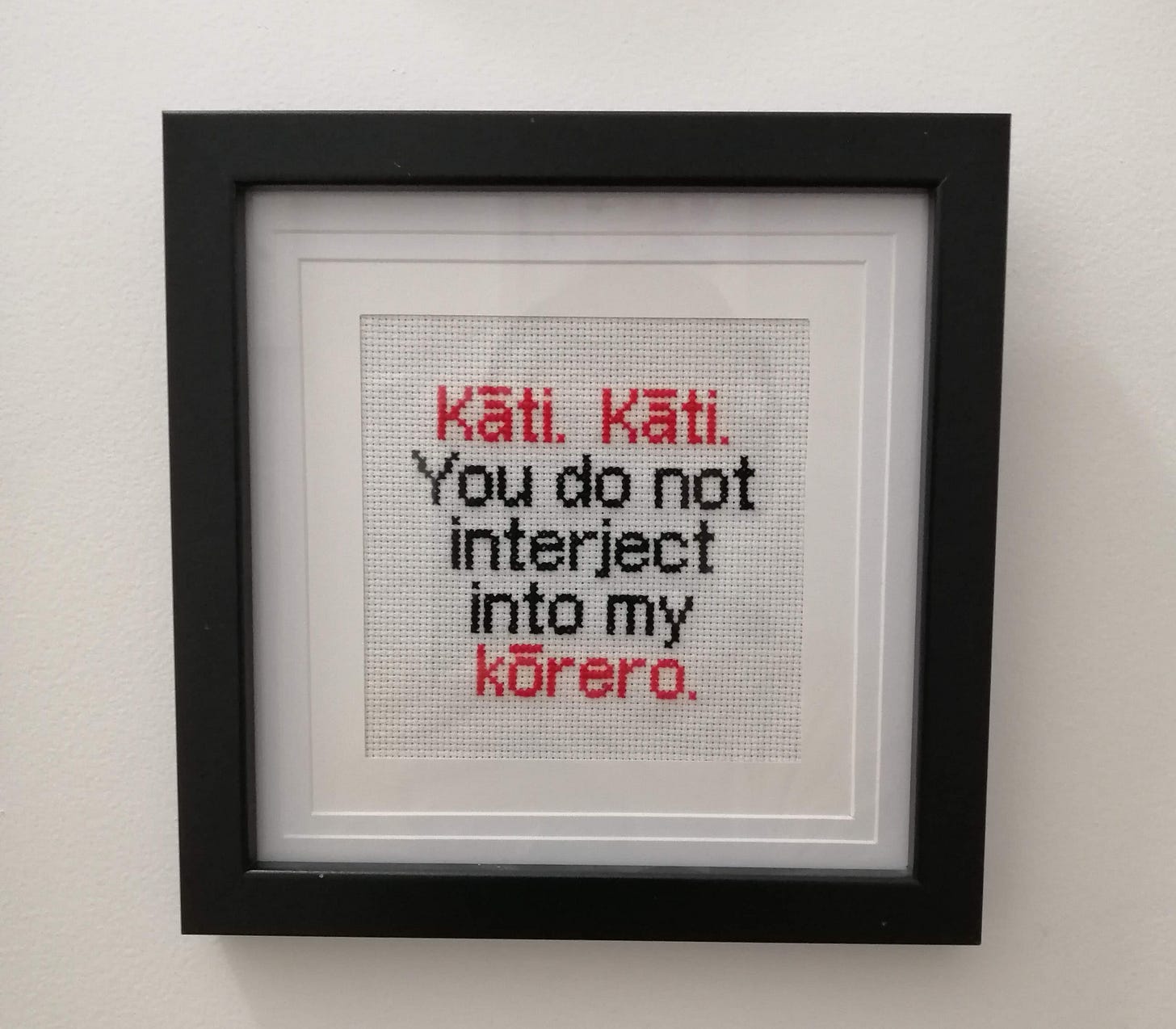 Cross stitch in a frame with text that says "kāti. Kāti. You do not interject into my kōrero"