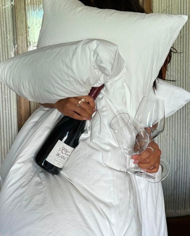 This may contain: a woman holding two wine glasses under a pillow