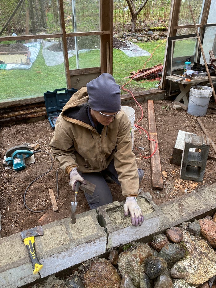 A woman hammers sand into cinderblocks.