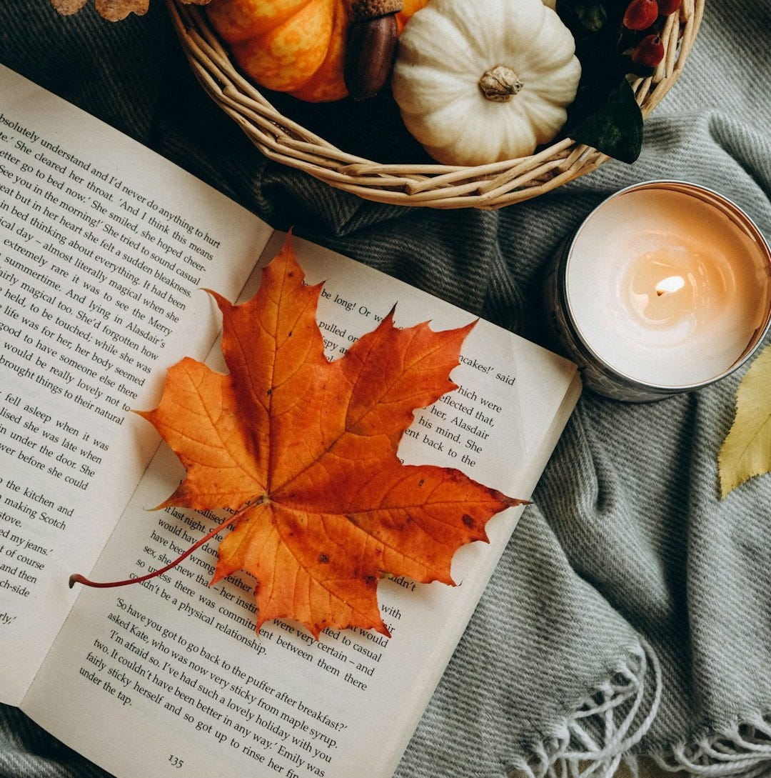 a basket of pumpkins and a candle on a table a basket of pumpkins and a candle on a table