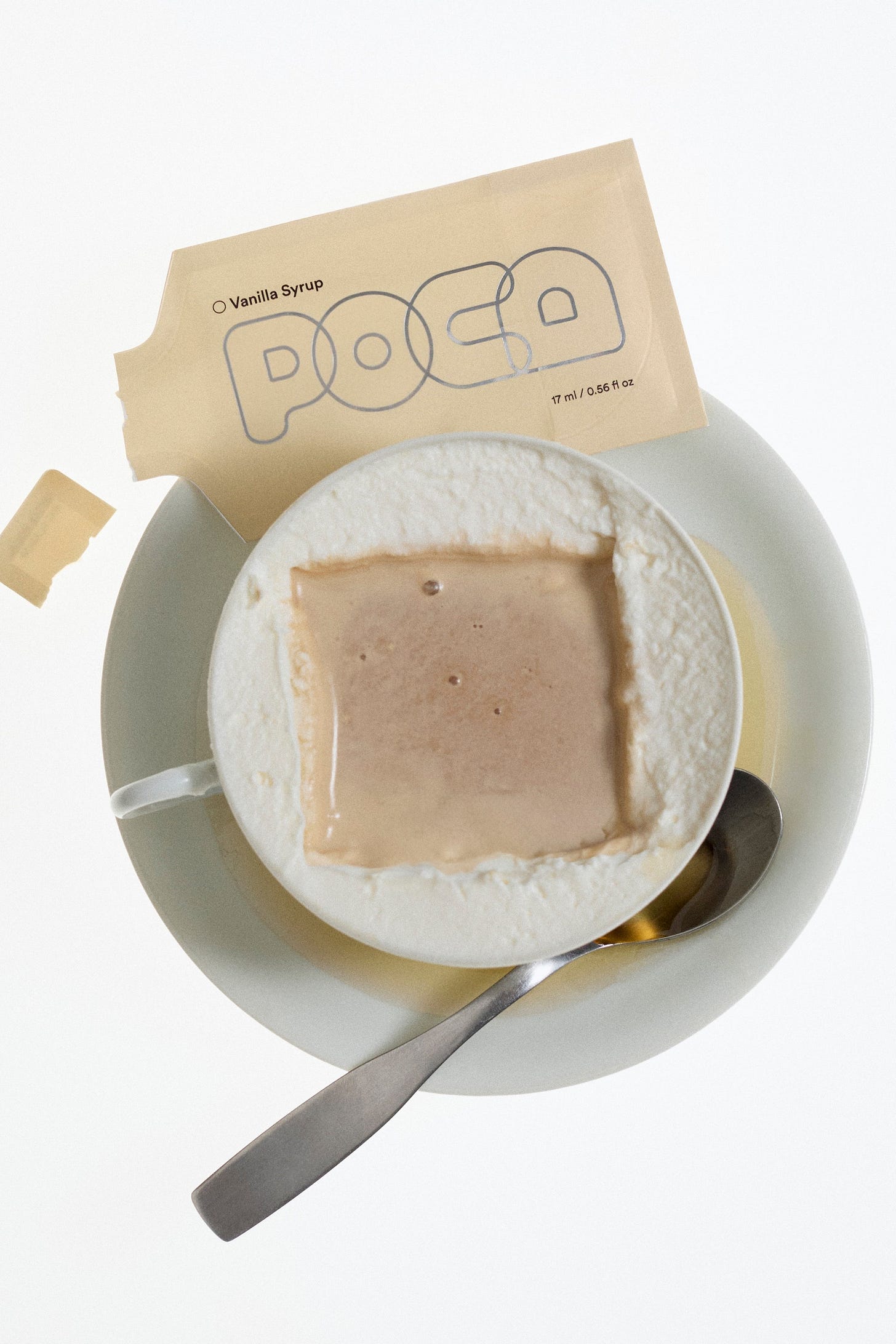 Vanilla syrup packet ripped opened and labeled 'POCA' laying on a cappuccino. Vanilla syrup packet ripped opened and labeled 'POCA' laying on a cappuccino.
