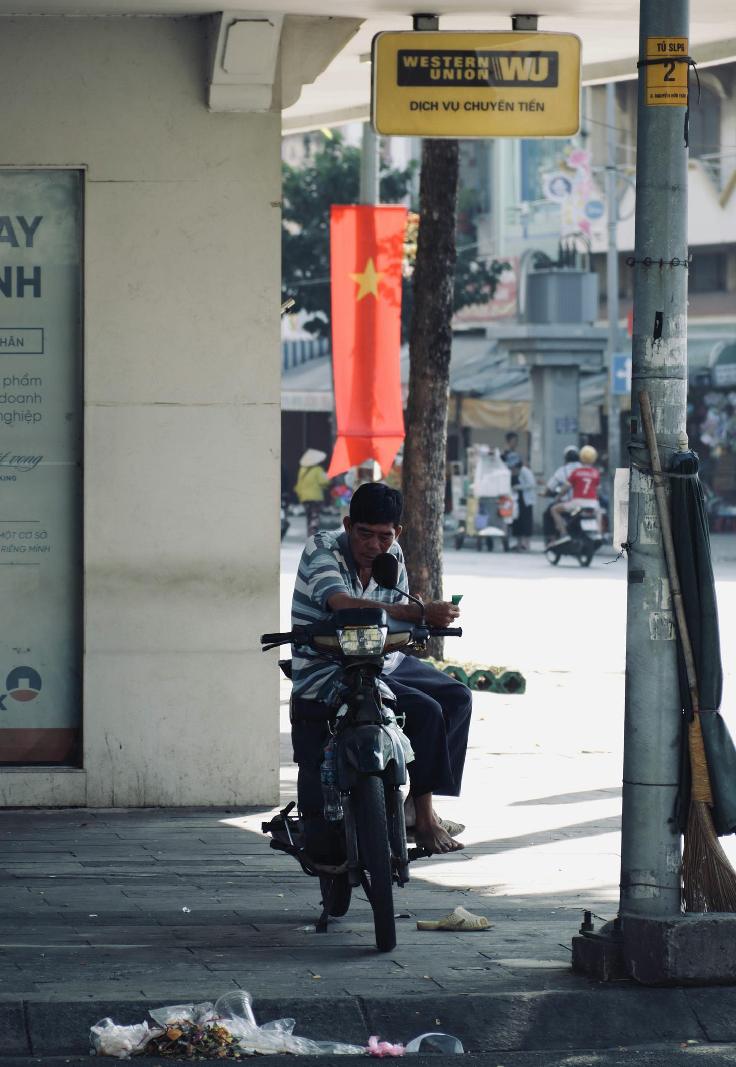 Man sitting on a two-wheeler under a Western Union sign in a different country