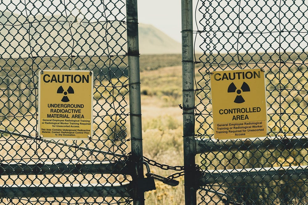 A chain link fence bearing caution signs: Radioactive Contamination. A chain link fence bearing caution signs: Radioactive Contamination.