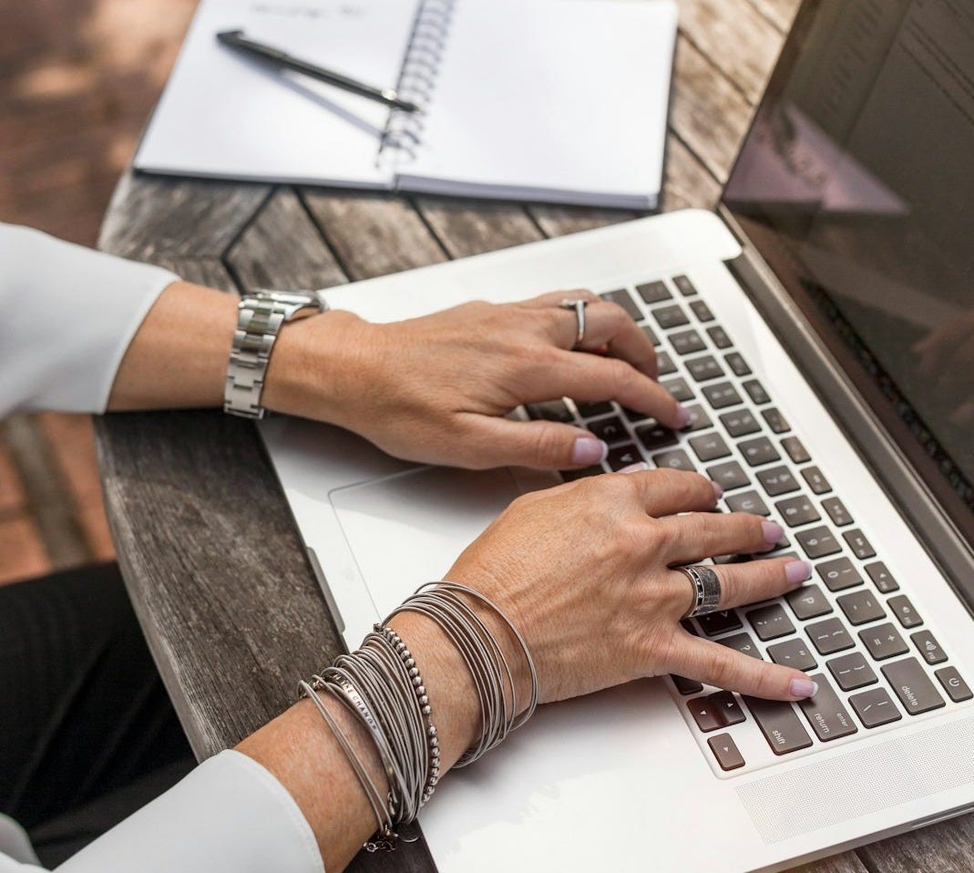 person typing on MacBook Pro on brown wooden table during daytime photo