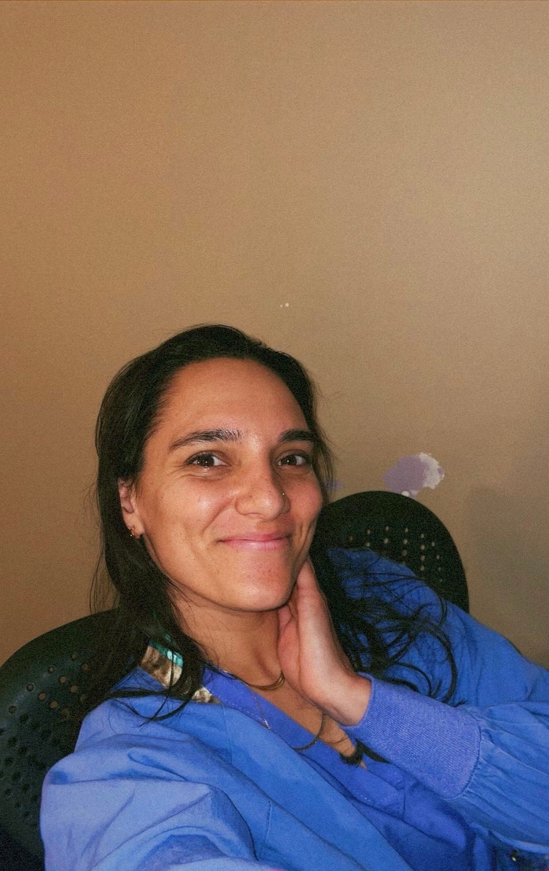 mia in blue scrubs and a desk chair smiling
