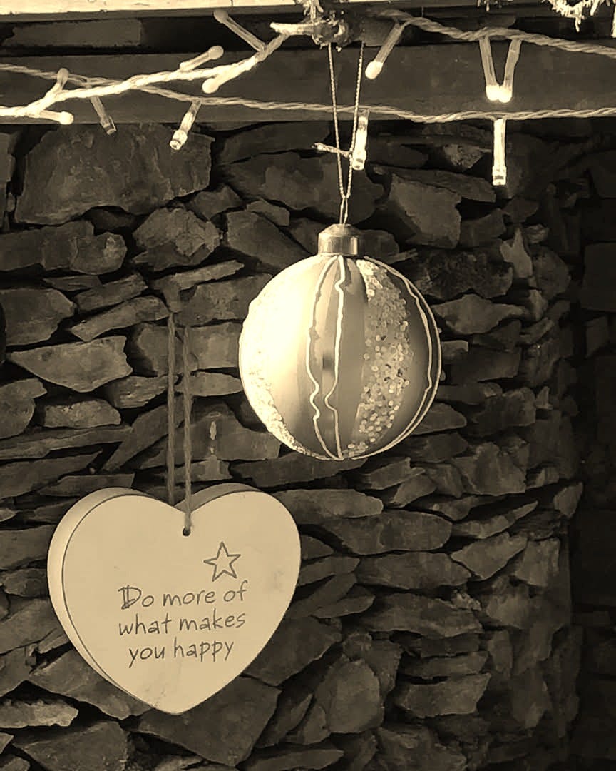 Christmas baubles on a garden wall. Heart-shaped says 'Do more of what makes you happy'