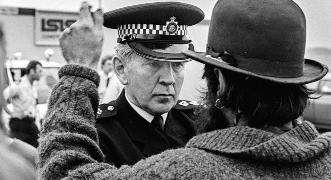 A black and white photo of a man wearing a jumper facing a police officer in uniform A black and white photo of a man wearing a jumper facing a police officer in uniform