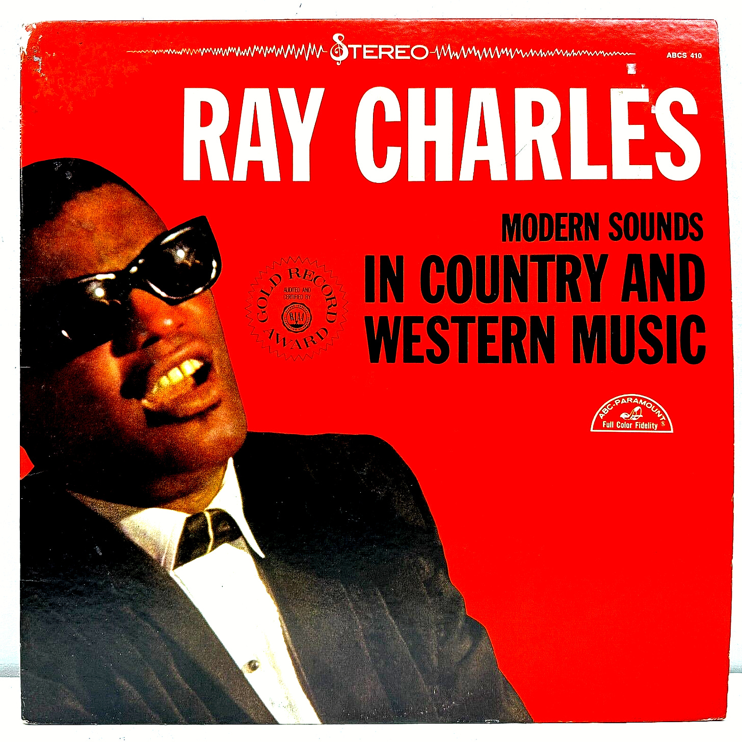 cover of Ray Charles: Modern Sounds in Country and Western Music; cover is red; picture shows Ray Charles, Black man with short hair and sunglasses in suit, singing cover of Ray Charles: Modern Sounds in Country and Western Music; cover is red; picture shows Ray Charles, Black man with short hair and sunglasses in suit, singing