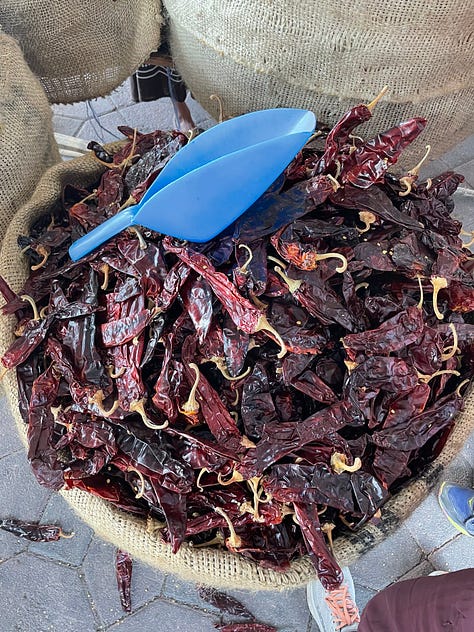 A nine image gallery showing dried chiles, coffee, cocoa beans, and sugar for sale at the market.