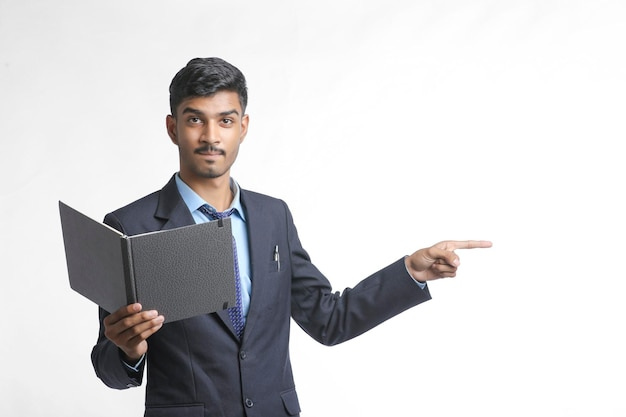 Successful young indian businessman or employee wearing suit and cheaking  dairy on white background. | Premium Photo