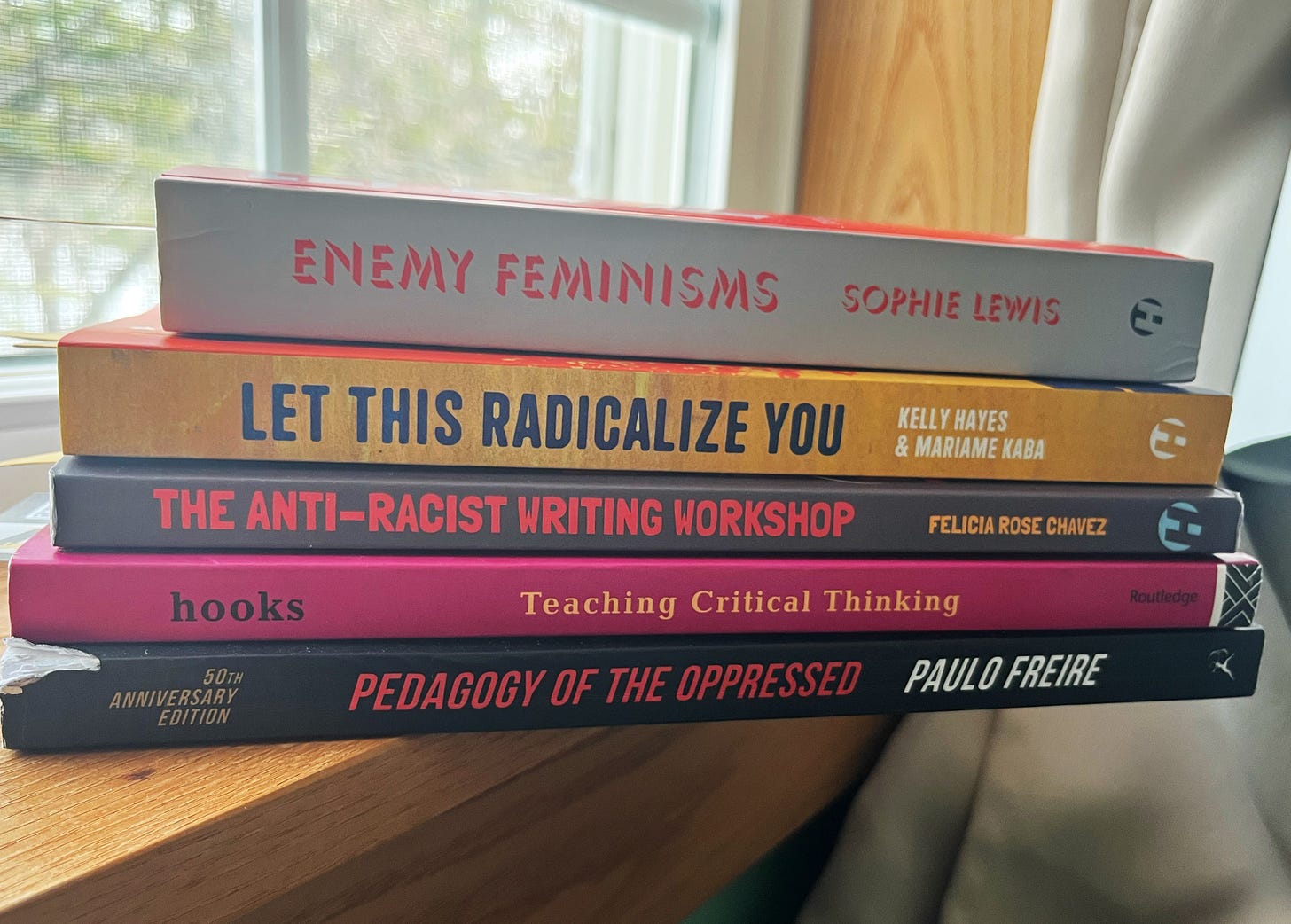Book stack from top to bottom: Enemy Feminisms by Sophie Lewis, Let This Radicalize You by Kelly Hayes and Mariame Kaba, The Anti-Racist Writing Workshop by Felicia Rose Chavez, Teaching Critical Thinking by bell hooks, and Pedagogy of the Oppressed by Paolo Freire Book stack from top to bottom: Enemy Feminisms by Sophie Lewis, Let This Radicalize You by Kelly Hayes and Mariame Kaba, The Anti-Racist Writing Workshop by Felicia Rose Chavez, Teaching Critical Thinking by bell hooks, and Pedagogy of the Oppressed by Paolo Freire