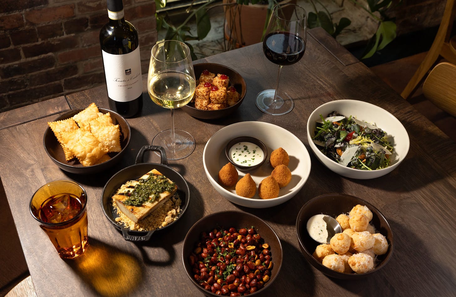 A table with plated food and a glass of wine.
