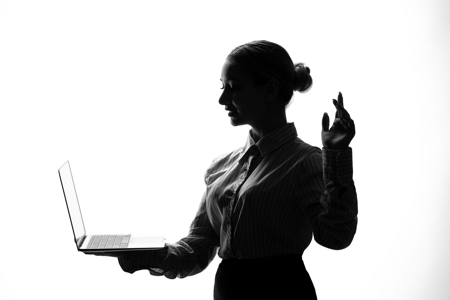 Silhouette of a woman holding a laptop against a white background.