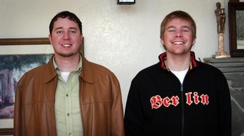 Cormac’s brother, wearing a brown leather jacket, stands smiling next to Cormac in a black 'Berlin' jacket in 2005.