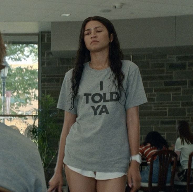 This may contain: a woman with her eyes closed standing in front of a man who is wearing a t - shirt that says i told ya