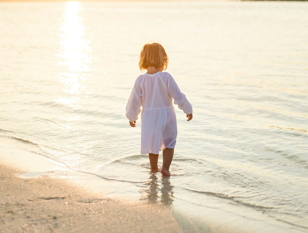 girl in white long sleeve shirt and white pants standing on beach during daytime girl in white long sleeve shirt and white pants standing on beach during daytime