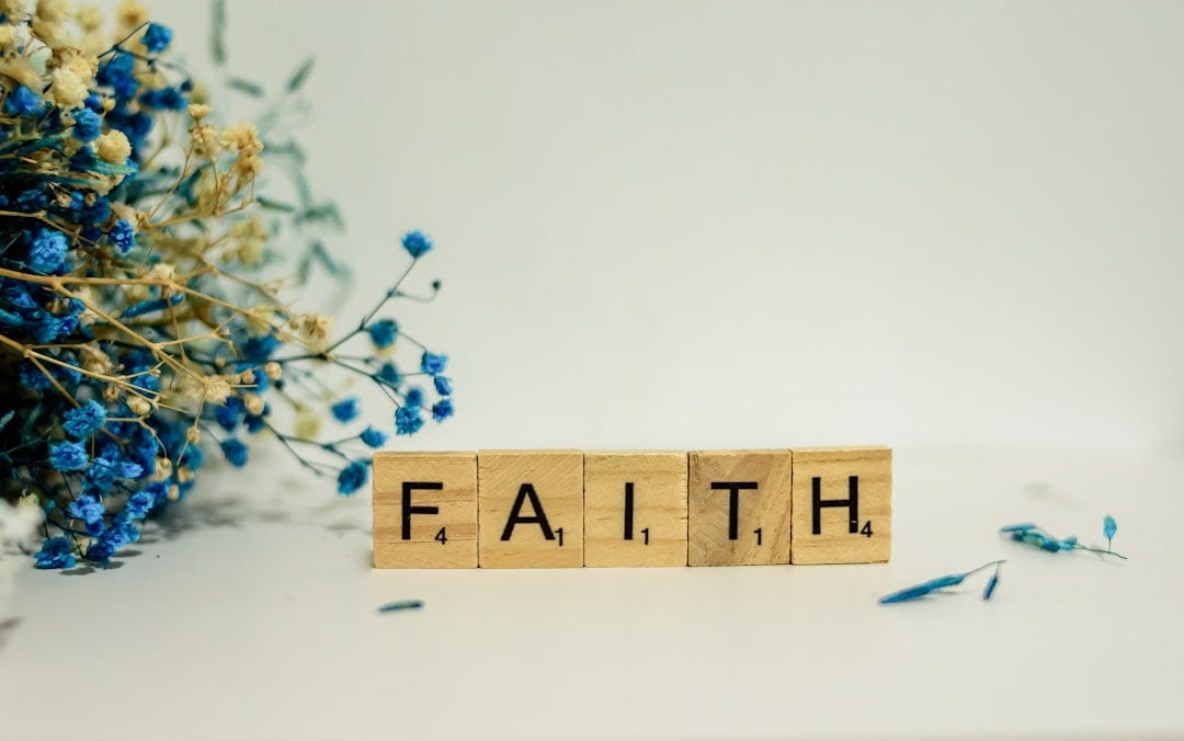 a wooden block that says faith next to blue flowers a wooden block that says faith next to blue flowers