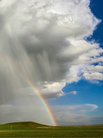 rainbow coming out of a cloud into sunny day