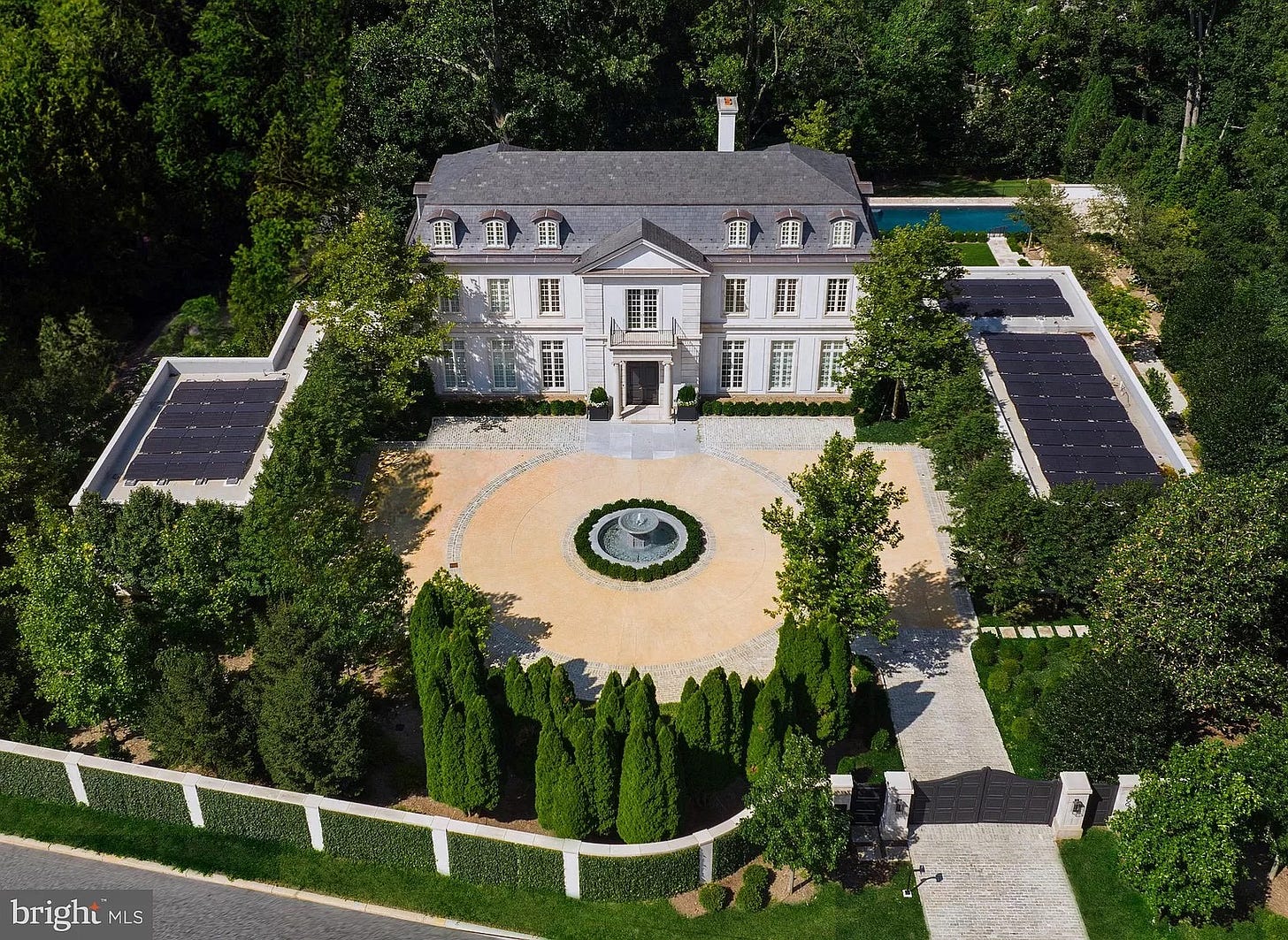 Aerial view of a large mansion with solar panels on two adjacent flat roofed structures — garages we guess. Aerial view of a large mansion with solar panels on two adjacent flat roofed structures — garages we guess.