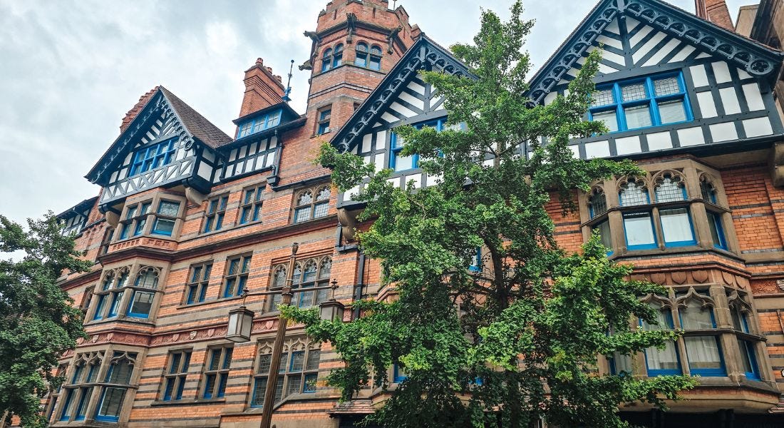 A row of brick buildings with blue framed windows with trees in front of them