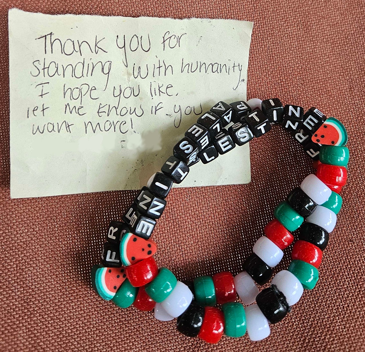 A note saying, "Thank you for standing with humanity" and "Free Palestine" bracelets. A note saying, "Thank you for standing with humanity" and "Free Palestine" bracelets.