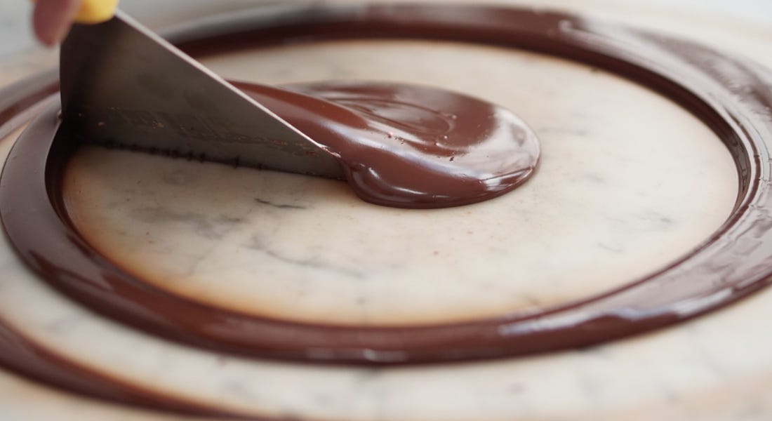 A grey marble worktop with a swirl of tempered chocolate on it A grey marble worktop with a swirl of tempered chocolate on it