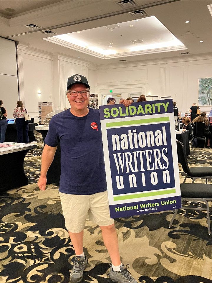 Kacey Carpenter holding National Writers Union sign and wearing a button at a writers event in Portland Oregon