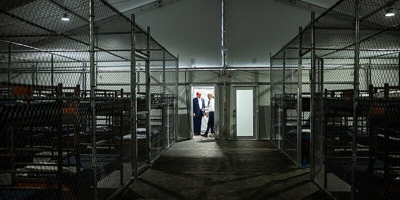 interior of Alligator Alcatraz showing cages on the left and the right, with bunk beds inside the cages. Reminiscent of a dog kennel. interior of Alligator Alcatraz showing cages on the left and the right, with bunk beds inside the cages. Reminiscent of a dog kennel.