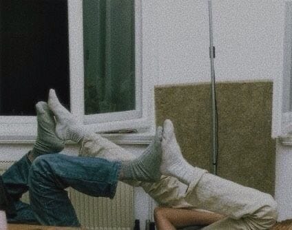 two people's legs up in the air with their feet touching