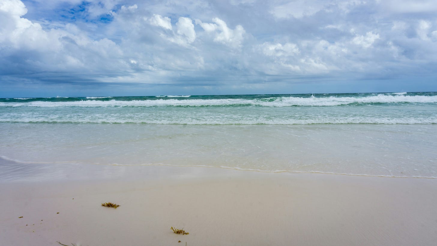 A beach scene with calm waves on a sunny day A beach scene with calm waves on a sunny day