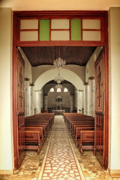 Free Explore the vintage interior of a church in Heliodora, Brazil, featuring chandeliers and wooden pews. Stock Photo