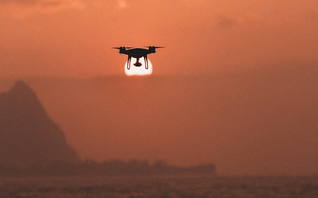 silhouette of drone hovering above body of water
