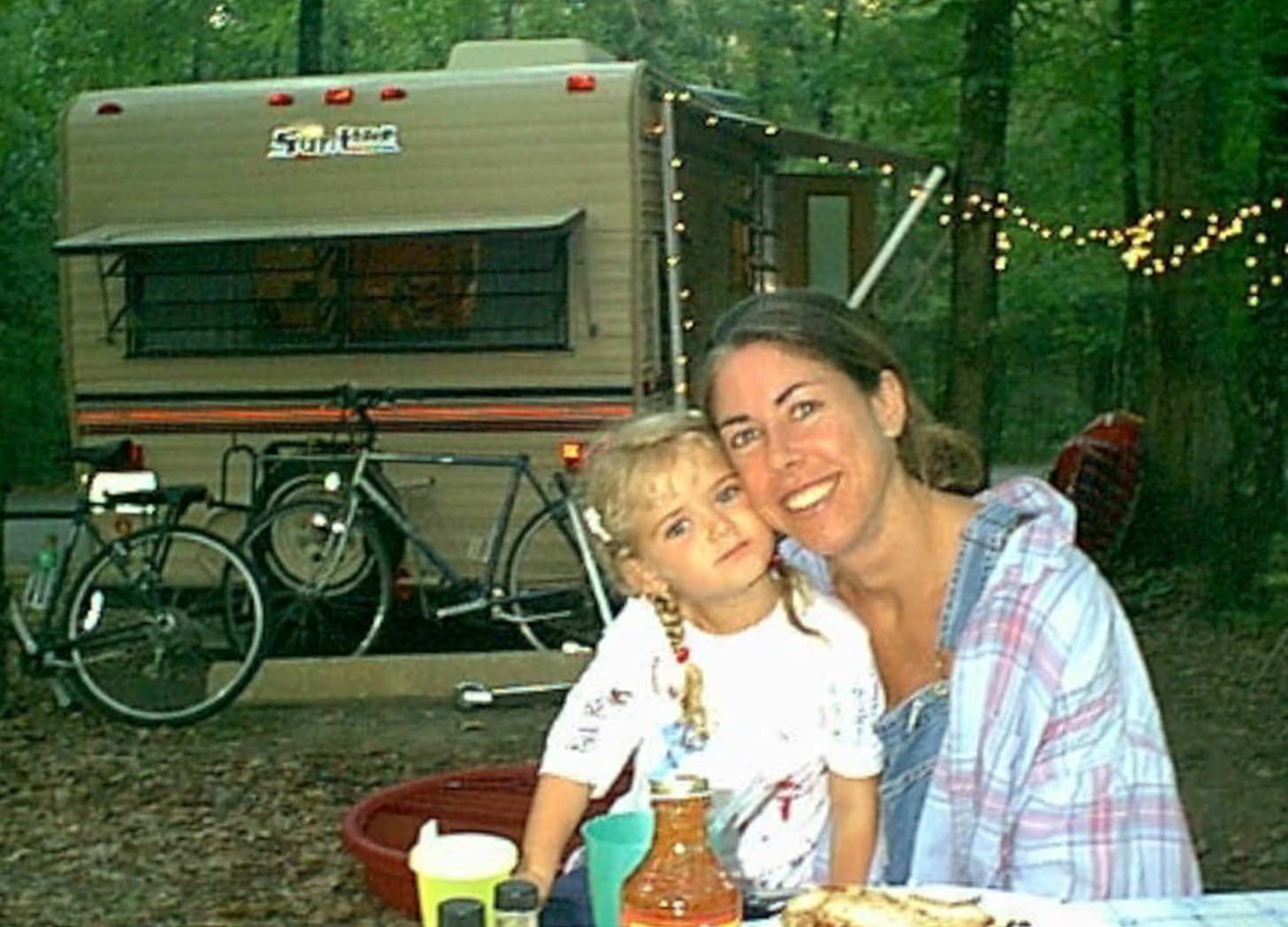 Woman and little girl at picnic table with travel trailer in background