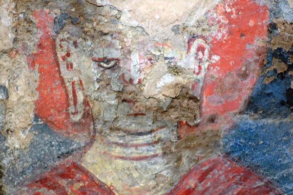 A placid Buddha stares from a cracked painting. 