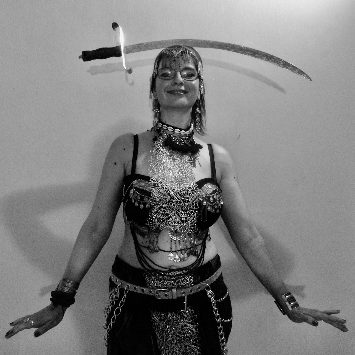 Woman in her 40s performing tribal fusion bellydance with sword balanced on head, wearing ornate costume with coin jewelry and headpiece, demonstrating embodied and powerful dance in midlife Woman in her 40s performing tribal fusion bellydance with sword balanced on head, wearing ornate costume with coin jewelry and headpiece, demonstrating embodied and powerful dance in midlife