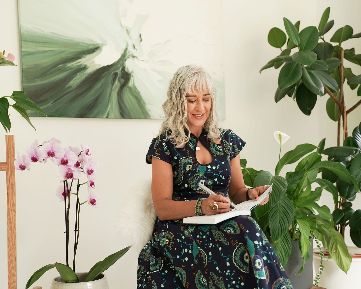 Sanjida sitting in her office writing in a notebook, surrounded by plants