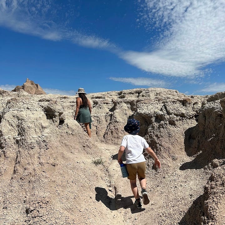 Two images show Nicole hiking through national parks. The first is of her on a heavily wooded trail in the Great Smokey Mountains, where she's warm but shaded. The second features her walking through dunes in Badlands National Park, where she felt like she was melting do death.