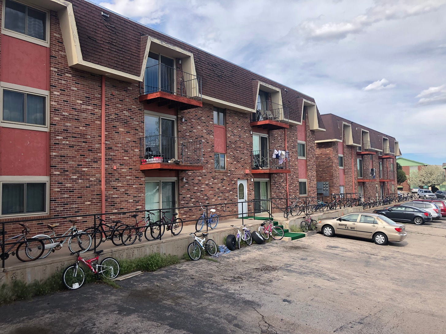 Two brick buildings overlook a parking lot in front of a gray, cloudy sky. Two brick buildings overlook a parking lot in front of a gray, cloudy sky.