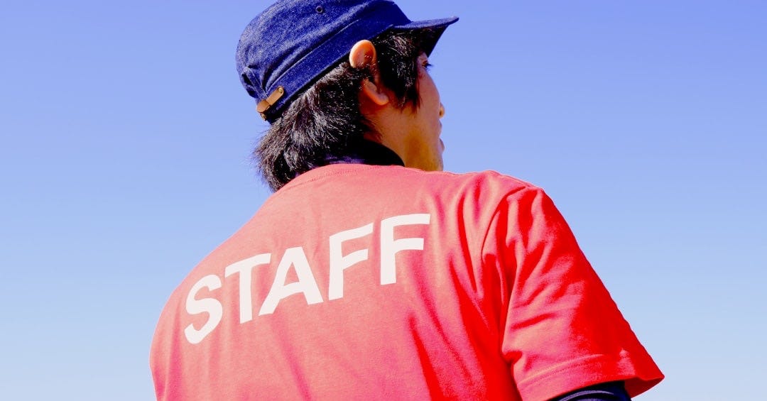 male staff wearing red t-shirt and blue hat standing male staff wearing red t-shirt and blue hat standing