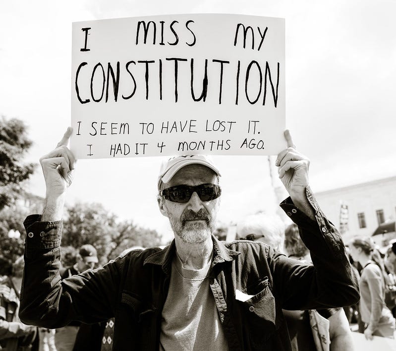 black and white photo of bearded man wearing sunglasses and a baseball cap, protesting outside the US Supreme Court. His handmade sign reads 'I miss my Constitution' in large letters, and in smaller print, 'I seem to have lost it. I had it 4 months ago.' black and white photo of bearded man wearing sunglasses and a baseball cap, protesting outside the US Supreme Court. His handmade sign reads 'I miss my Constitution' in large letters, and in smaller print, 'I seem to have lost it. I had it 4 months ago.'