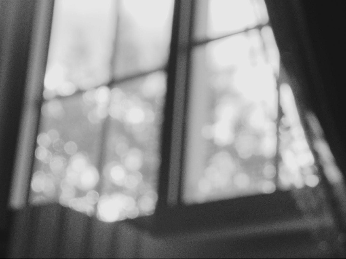 Black and white window with the curtains open, artistically blurred to create a bokeh effect