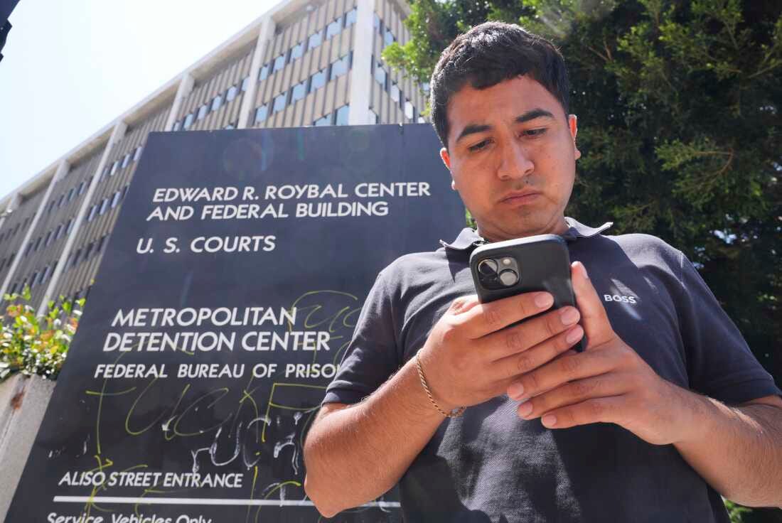Alejandro Barranco checks his phone as he arrives to check on his father Narciso, who was detained by federal agents, outside the Metropolitan Detention Center on Monday, June 23, in Los Angeles.