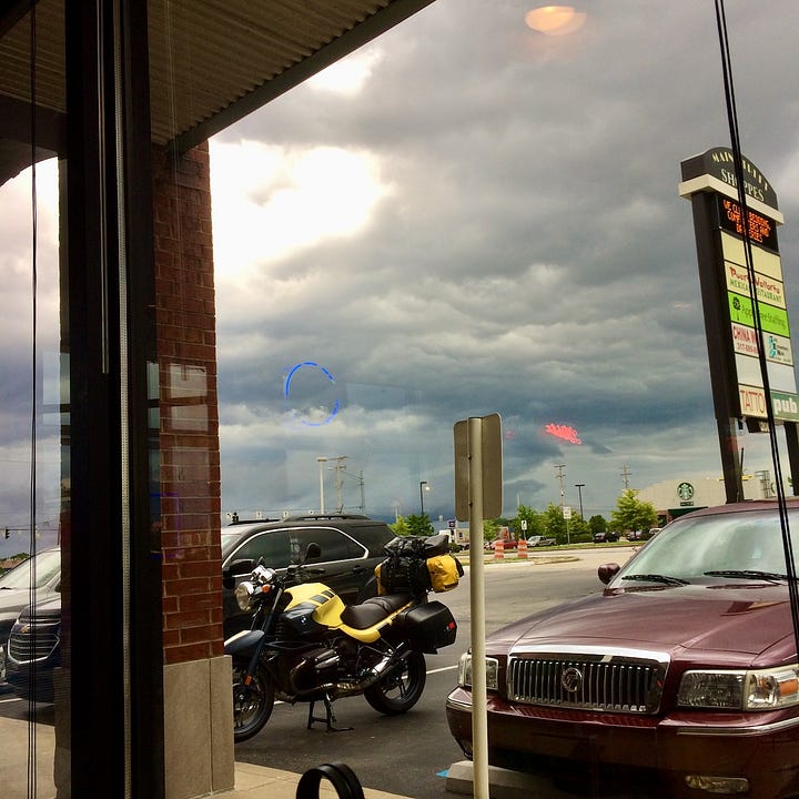 Jess sits at a table with a plate of chicken wings; in another picture the bike is parked in a lot while it rains